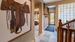 A hallway with a framed equestrian statue, a wooden staircase, and a view of a bedroom with a bed and window. - Slopeside Chalet 3 Bedroom Townhouse by Alpine Lodging Telluride (Telluride)