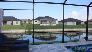 A pool area with lounge chairs, a small pool, and a view of houses in the background.