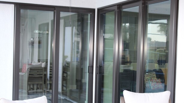 A room with a sliding glass door leading to an outdoor area. There are two white cushioned chairs in the room.