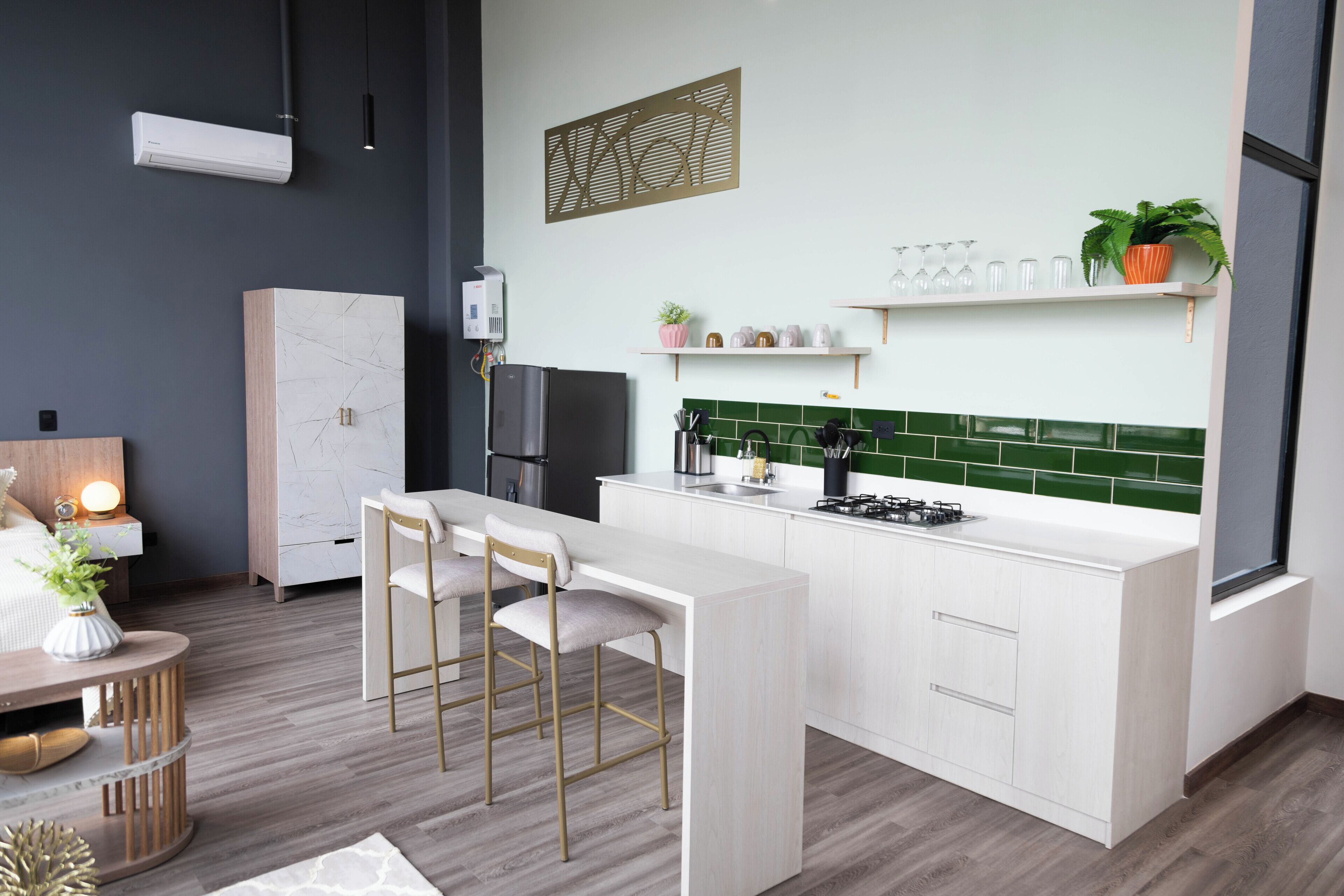 Eine moderne Küche mit weißen Schränken, einer grünen Spritzschutzwand und einer Bar mit Hockern.