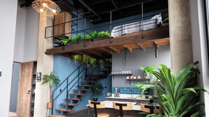 Una cocina moderna con escalera de madera, taburetes de bar y plantas en macetas.