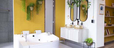 Une salle de bain moderne avec une grande baignoire, un meuble-lavabo blanc et plusieurs miroirs.