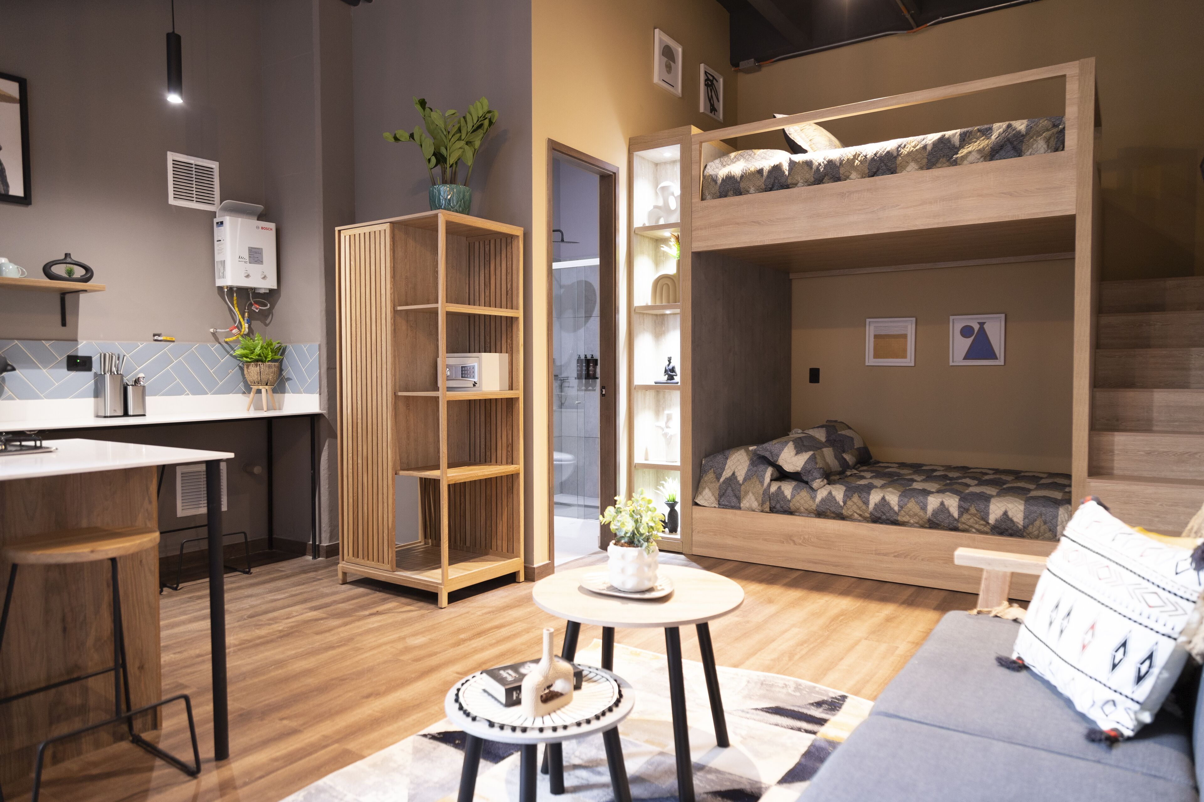Een compacte leefruimte met een stapelbed, een kitchenette, een eethoek en een kleine zithoek.