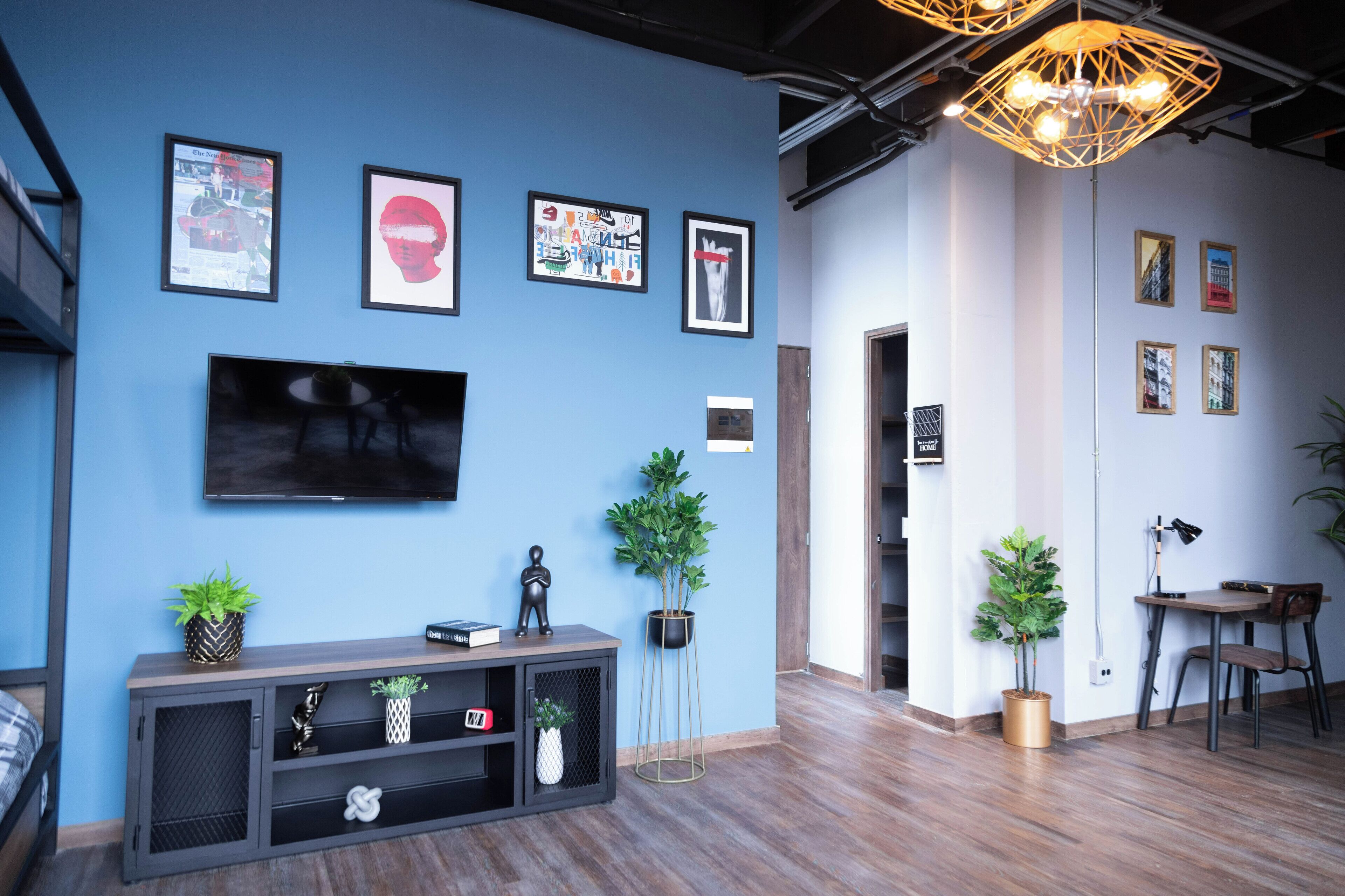 Una sala de estar moderna con pared azul, un televisor de pantalla plana, una consola de madera y varias obras de arte enmarcadas.