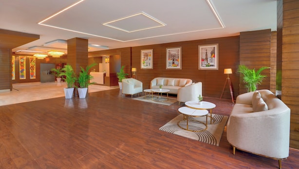 Een ruime lobby met een houten vloer, modern meubilair en sfeervolle verlichting.