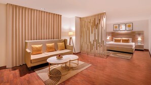 Een moderne hotelkamer met een bank, een rond salontafeltje, een bed en een nachtkastje.