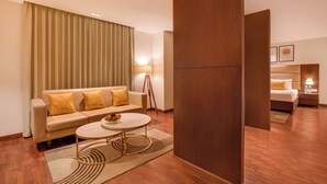 Een hotelkamer met een bank, een ronde salontafel, een lamp en een bed.