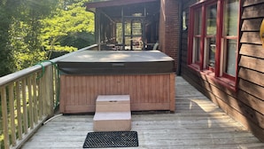 A hot tub on a wooden deck with a glass enclosure, steps leading up to it, and a view of the surrounding trees. - Farmhouse located on river with Mountain View-Wifi/Cable (Walland)