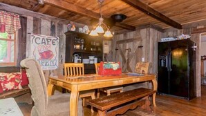 A rustic wooden interior with a wooden dining table, chairs, and a bench. There is a refrigerator, a shelf with various items, and a sign that reads "CAFE OPEN". - Farmhouse located on river with Mountain View-Wifi/Cable (Walland)