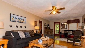 A cozy living room with a dark-colored sofa, a wooden coffee table, and a ceiling fan. - Farmhouse located on river with Mountain View-Wifi/Cable (Walland)