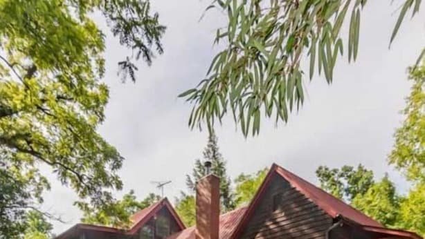 A two-story wooden cabin with a red roof, a covered porch, and a small deck. - Farmhouse located on river with Mountain View-Wifi/Cable (Walland)