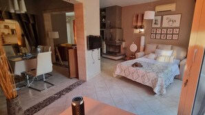 Une chambre d’hôtel équipée d’un lit, d’un bureau, d’une chaise, d’une télévision et d’une cheminée.