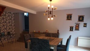 Un comedor con una mesa y sillas de madera, un adorno geométrico en la pared y una araña.