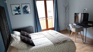 Un dormitorio con cama, un escritorio con televisor y una ventana con cortinas.