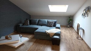 Una sala de estar moderna con un sofá modular, una mesita de centro, una mesita auxiliar y un tragaluz.