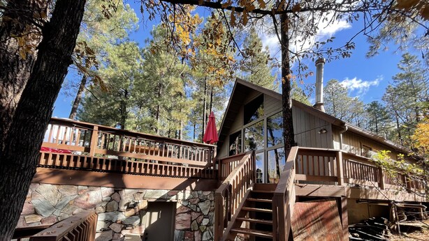 Eine Holzhütte mit Steinuntergrund, einer Holzterrasse und einer Treppe zu einem Balkon.