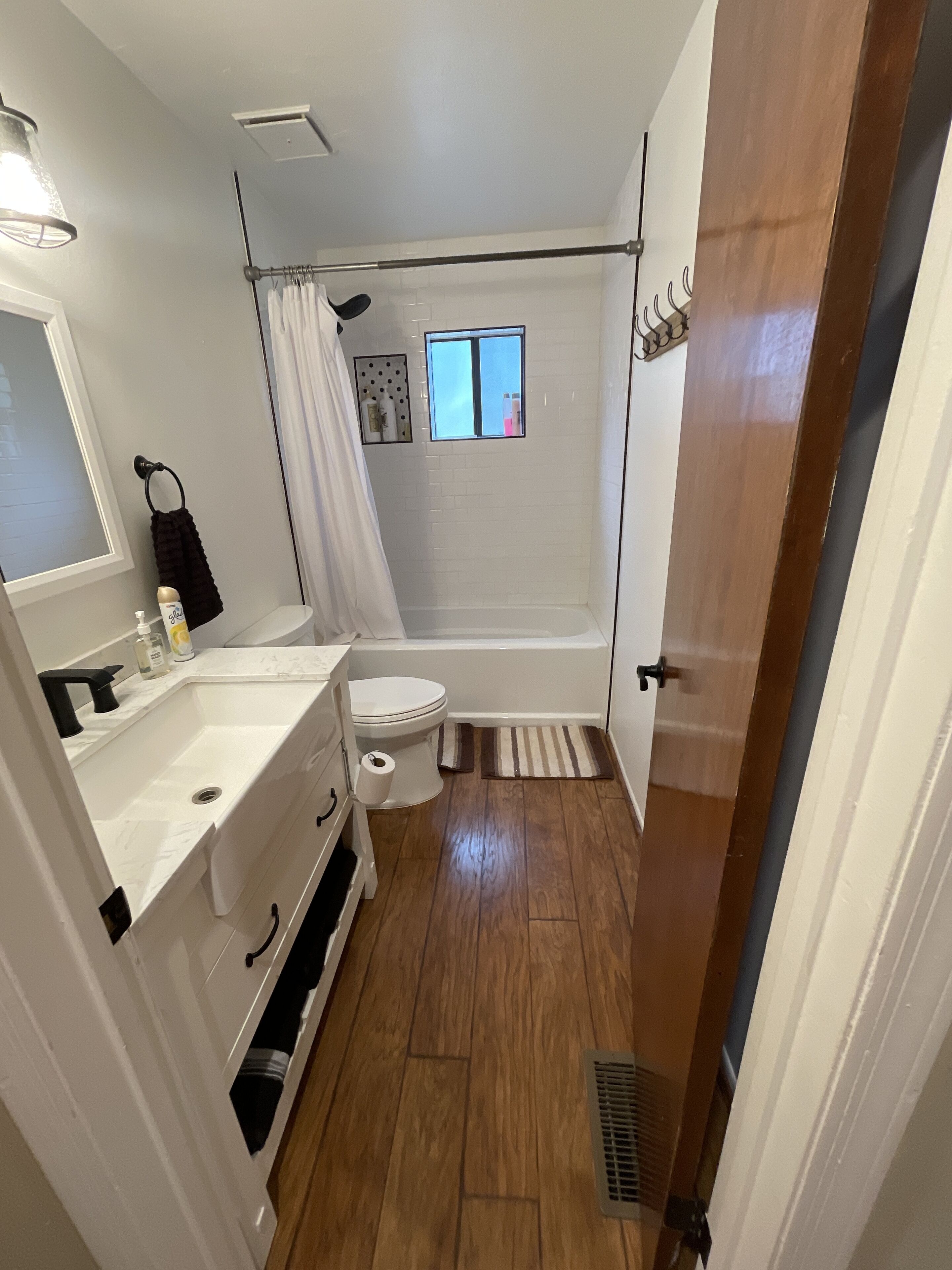 Un baño pequeño con lavamanos, inodoro y zona de ducha blancos.