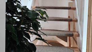 Eine Holztreppe mit weißer Geländer und einer Pflanze daneben.