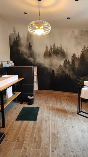 A modern bathroom with a wooden floor, a white sink, a black cabinet, and a large mirror. - The Polly vacation home is a small, cozy townhouse (Taucha)