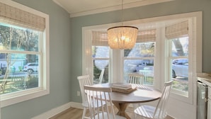 A dining area with a round table, white chairs, and a chandelier. - Beautiful beach cottage 1/2 mile to the Sandy Shore! (Fernandina Beach)