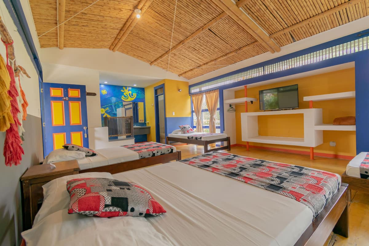 A room with two beds, a TV, and a TV stand.