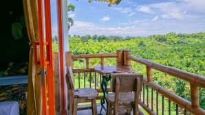 A balcony with a table and chairs, a wooden railing, and a view of a lush green landscape. - Hotel Campestre La Aldea (Montenegro)