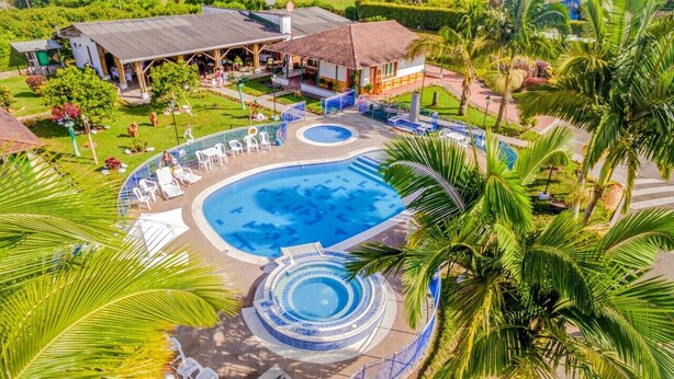 A resort with a large swimming pool, a circular hot tub, and a covered outdoor seating area surrounded by palm trees. - Hotel Campestre La Aldea (Montenegro)