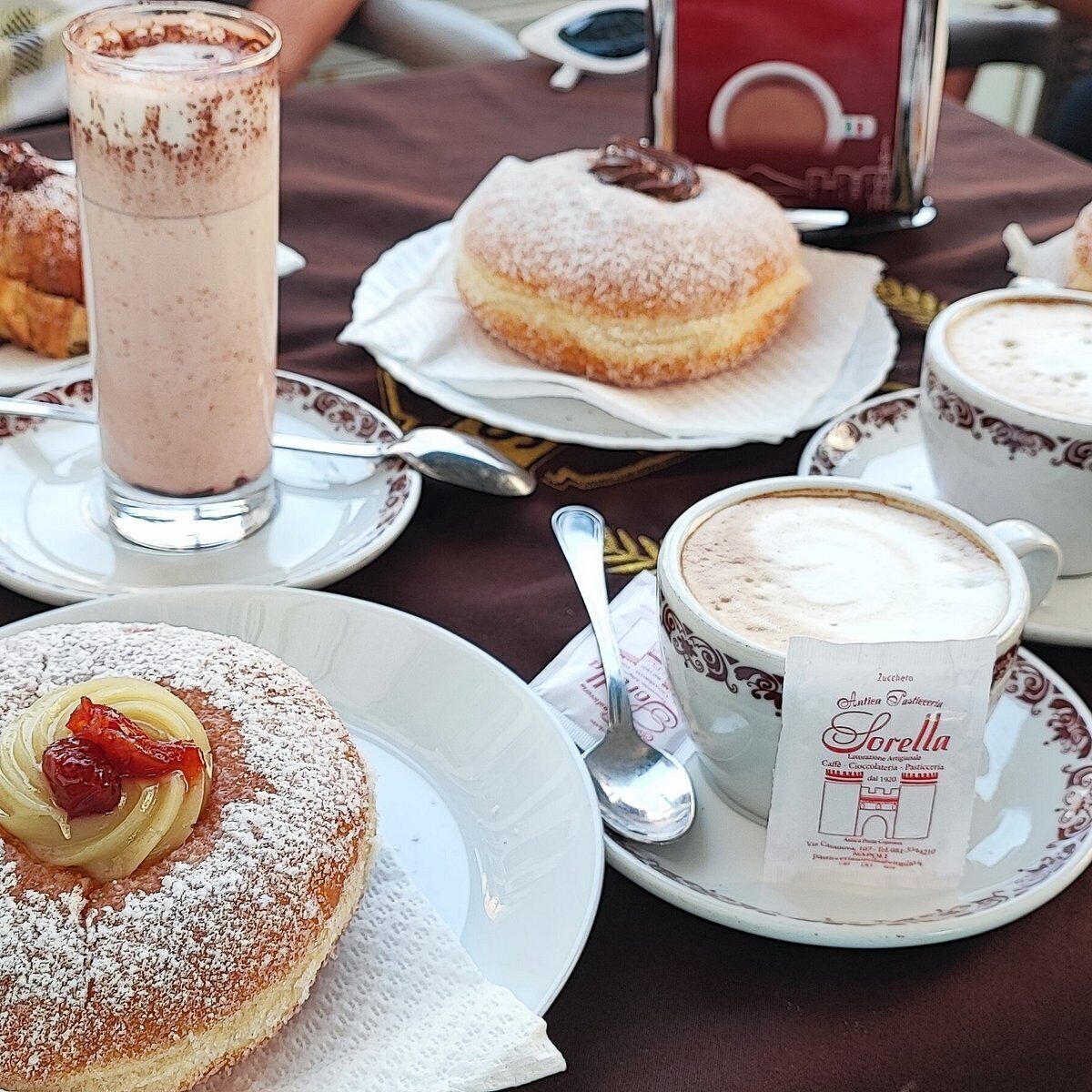 A table with a variety of desserts including a frosted pastry, a chocolate-covered donut, and a chocolate beverage.