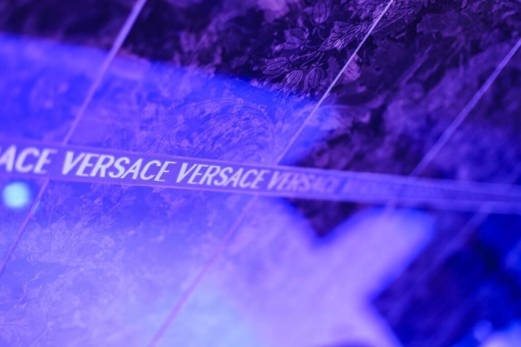 A close-up of a fabric with the text "VERSACE VERSACE VERSACE VERSACE VERSACE VERSACE VERSACE VERSACE VERSACE VERSACE VERSACE VERSACE VERSACE VERSACE VERSACE VERSACE VERSACE VERSACE VERSACE VERSACE VERSACE VERSACE VERSACE VERSACE VERSACE VERSACE VERSACE VERSACE VERSACE VERSACE VERSACE VERSACE VERSACE VERSACE VERSACE VERSACE VERSACE VERSACE VERSACE VERSACE VERSACE VERSACE VERSACE VERSACE VERSACE VERSACE VERSACE VERSACE VERSACE VERSACE VERSACE VERSACE VERSACE VERSACE VERSACE VERSACE VERSACE VERSACE VERSACE VERSACE VERSACE VERSACE VERS