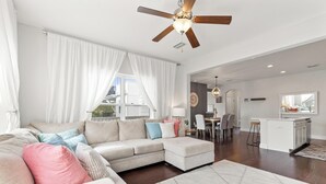 A spacious living room with a large sectional sofa, a dining area, and a kitchen. - 30A Beach House - Whatcha Dune by PHG (Panama City Beach)