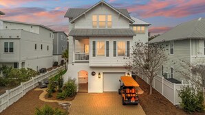 A two-story residential house with a covered garage and a driveway. - 30A Beach House - Whatcha Dune by PHG (Panama City Beach)