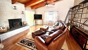 A living room with a fireplace, a sofa, a TV, and a bookshelf. - Manitou Midcentury with great location (Manitou Springs)