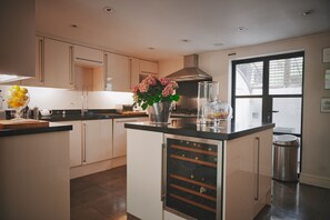 Eine moderne Küche mit Weinkühlschrank, Edelstahlgeräten und einem großen Fenster.