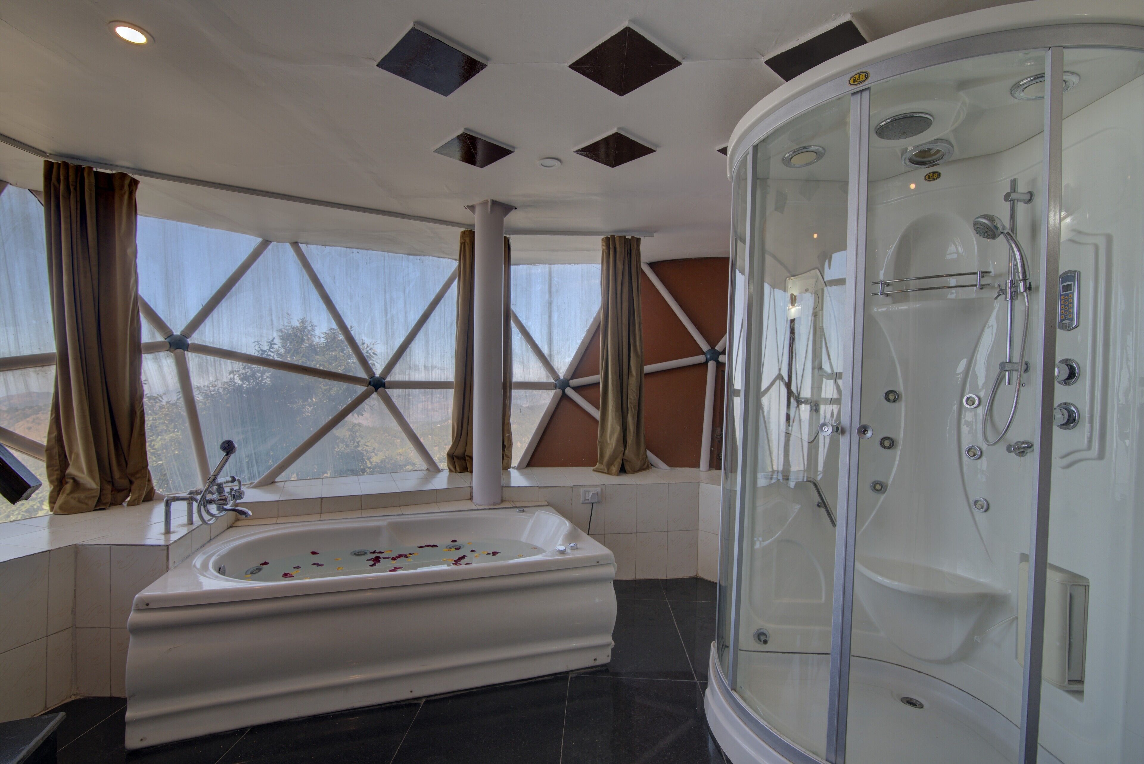 A modern bathroom with a freestanding bathtub, a glass-enclosed shower, and large windows with curtains.
