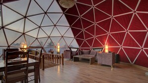 A spacious interior with a geometric ceiling structure, wooden flooring, and a seating area with a table and chairs. - Tarika Resort and Spa (Kandaghat)