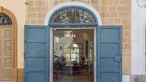 Entrada de un edificio con puerta de vidrio, pared de piedra y una puerta de madera a la izquierda.