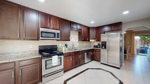 Una cocina moderna con armarios de madera oscura, electrodomésticos de acero inoxidable y encimera de granito.