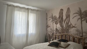 A bedroom with a bed, a desk, and a mural of a tropical scene. - Charming house in the Provencal Baronies (L'Épine)
