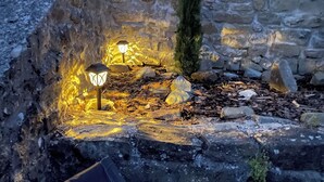 A stone wall with a small garden area featuring a stone bench and a lantern. - Charming house in the Provencal Baronies (L'Épine)