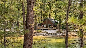 A cabin surrounded by trees and a pond.