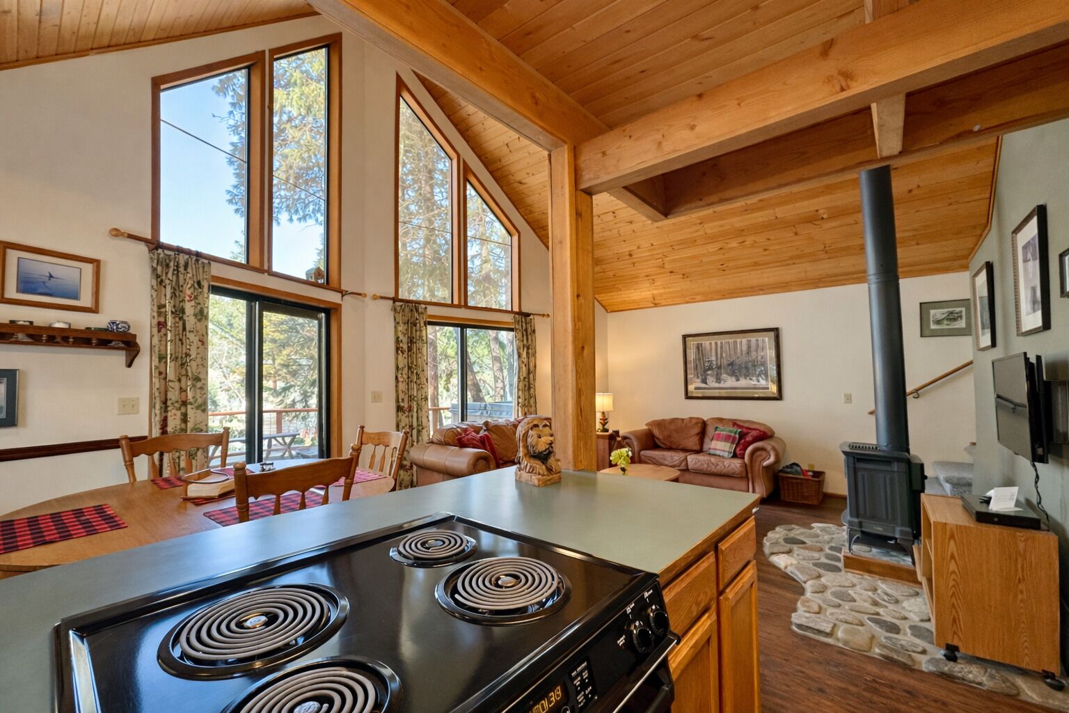 A spacious living area with a large wooden dining table, a kitchen with a black stove, and a cozy seating area with a fireplace.