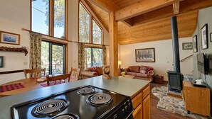 A spacious living area with a large wooden dining table, a kitchen with a black stove, and a cozy seating area with a fireplace.
