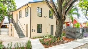 A two-story building with a beige exterior, a staircase leading to the entrance, and a tree in the front yard. - Lovely Apartment Near Brickell 1 (Miami)