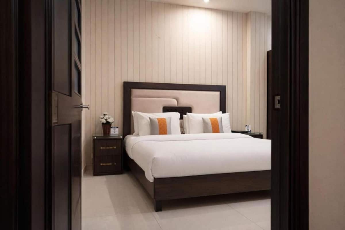 Une chambre à coucher comprenant un lit, des tables de chevet, une commode et un luminaire fixé au mur.