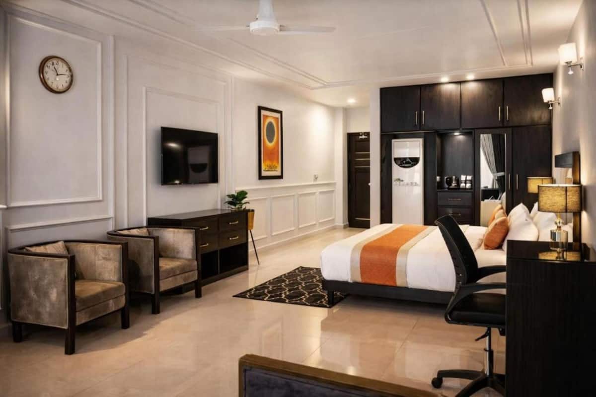 Une chambre d’hôtel moderne équipée d’un lit, d’un bureau, d’une chaise, d’une télévision et d’une armoire.
