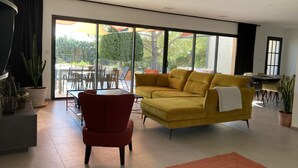 Ein modernes Wohnzimmer mit einem gelben Sofa, einem roten Sessel und einer Glastür zu einer Außenpatio.