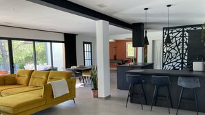 Eine moderne Küche mit Kochinsel, Barhocker und einem Essbereich mit Tisch und Stühlen.