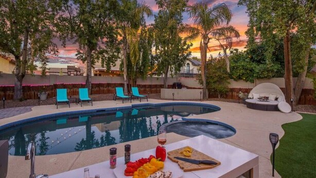 Zona de piscina al aire libre con bar, sillas de descanso y vistas al atardecer.