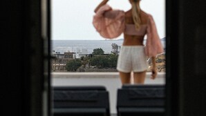 A person standing at a doorway, looking out at a cityscape.