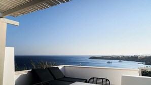 A balcony with a view of the sea, a table, and two chairs.